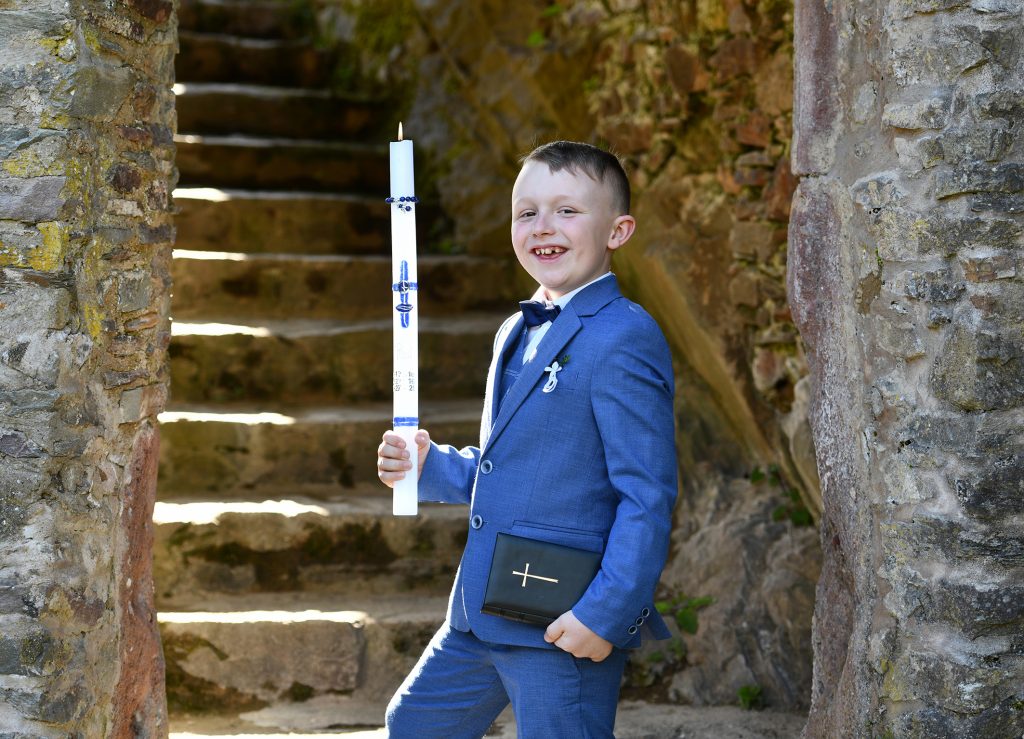 Natürliche Kommunionfotos - Lachender Junge im blauen Anzug vor rustikaler Steintreppe