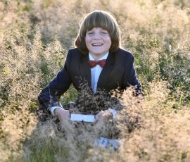 Kommunionfotos in der Natur - Junge in der Wiese sitzend